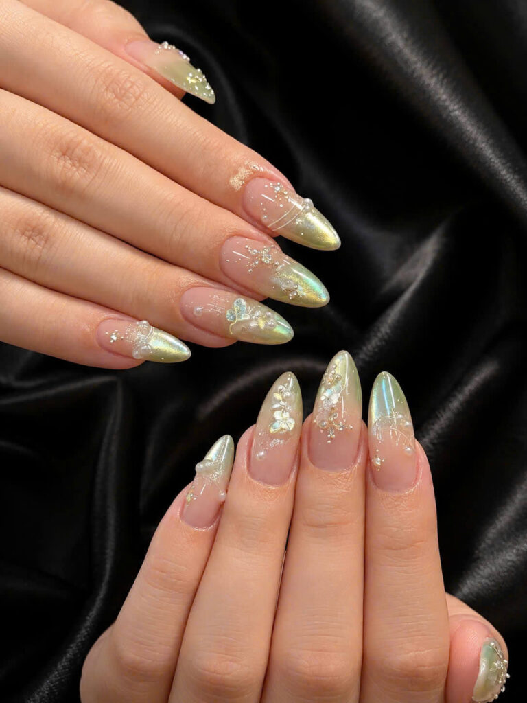 Long almond nails with shimmering gold tips and butterfly embellishments