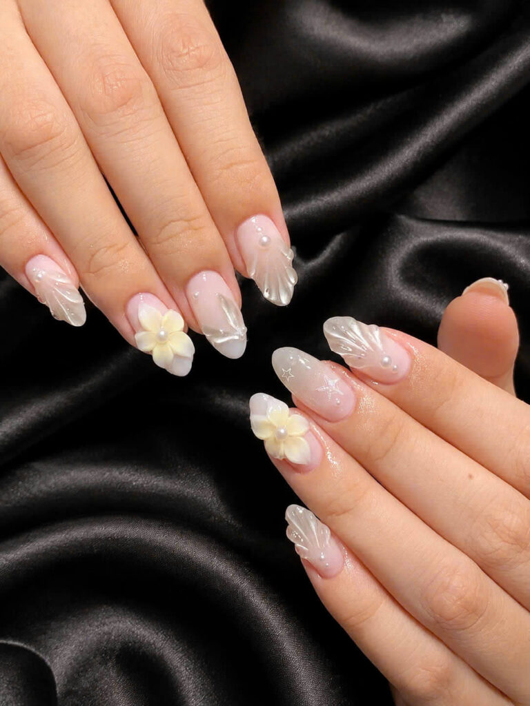 Almond nails with sculpted shells, pearls and pale yellow flowers